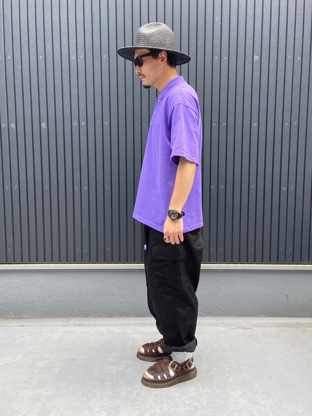 パープル系のポロシャツ、ブラック系のカーゴパンツ、ブラウン系のシューズを着用したメンズの夏コーディネートの2枚目の写真