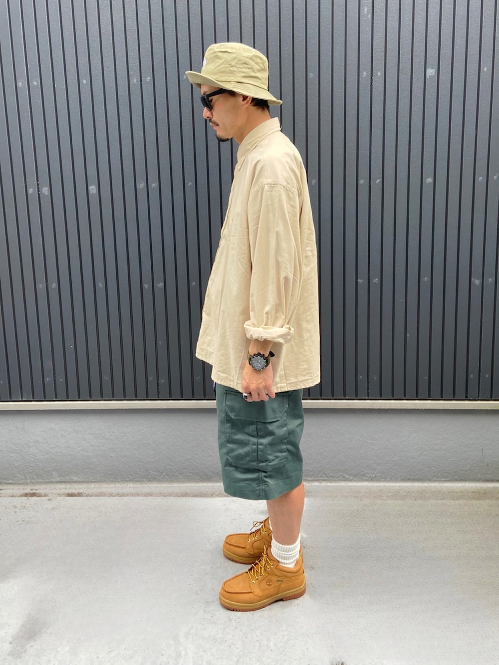 ベージュ系のシャツ/ブラウス、グリーン系のパンツ、イエロー系のブーツを着用したメンズの夏コーディネートの2枚目の写真