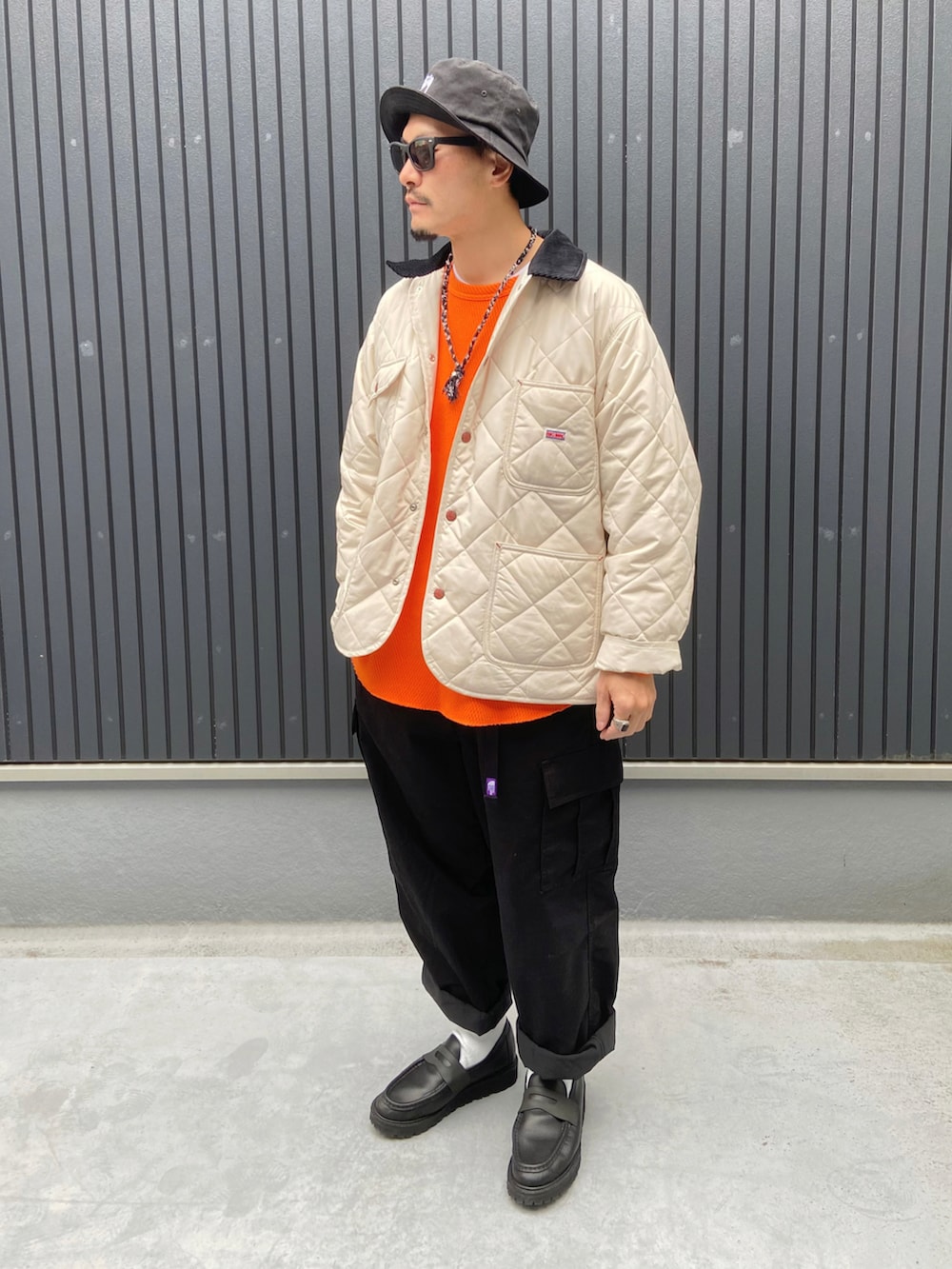 ホワイト系のカバーオール、オレンジ系のTシャツ/カットソー、ブラック系のカーゴパンツを着用したメンズの冬コーディネートの3枚目の写真