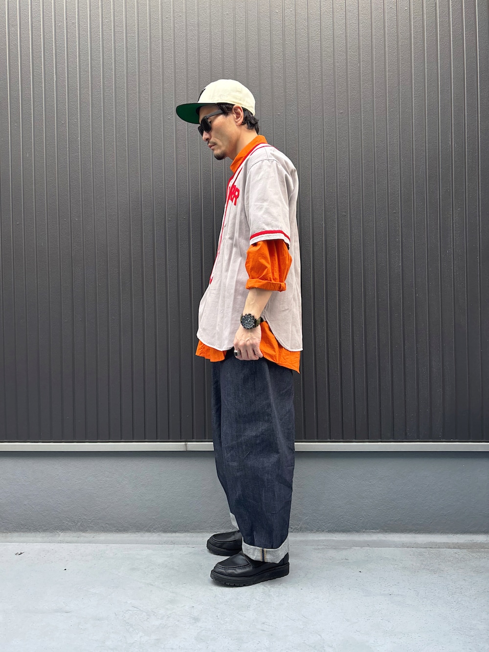 グレー系のシャツ/ブラウス、オレンジ系のトップス、ブルー系のデニムパンツを着用したメンズの春コーディネートの2枚目の写真