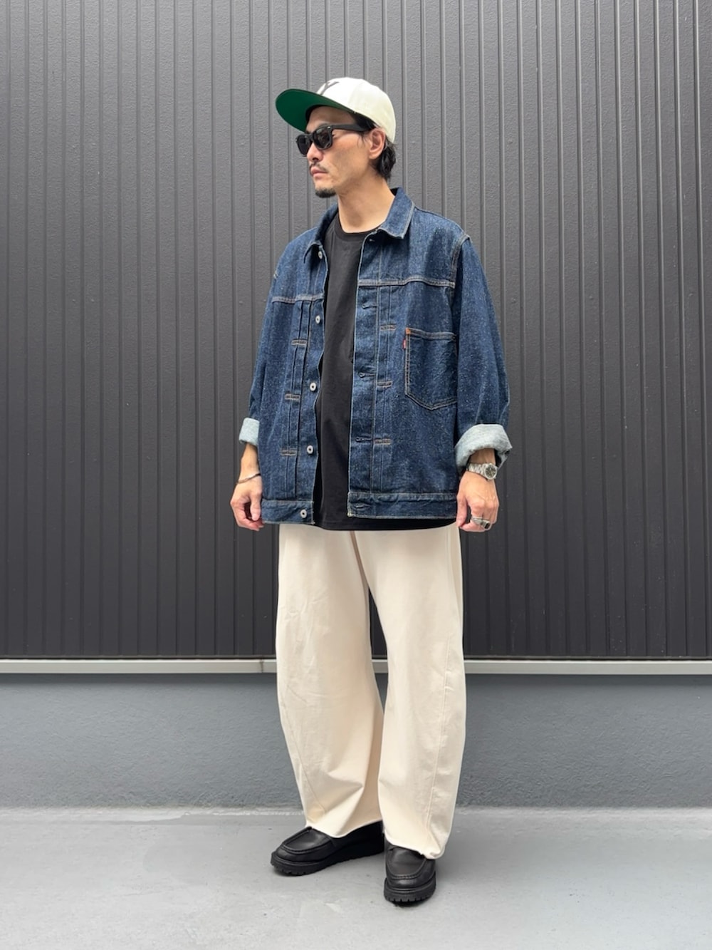 ブラック系のTシャツ/カットソー、ブルー系のデニムジャケット、ホワイト系のスウェットパンツを着用したメンズの秋コーディネートの3枚目の写真