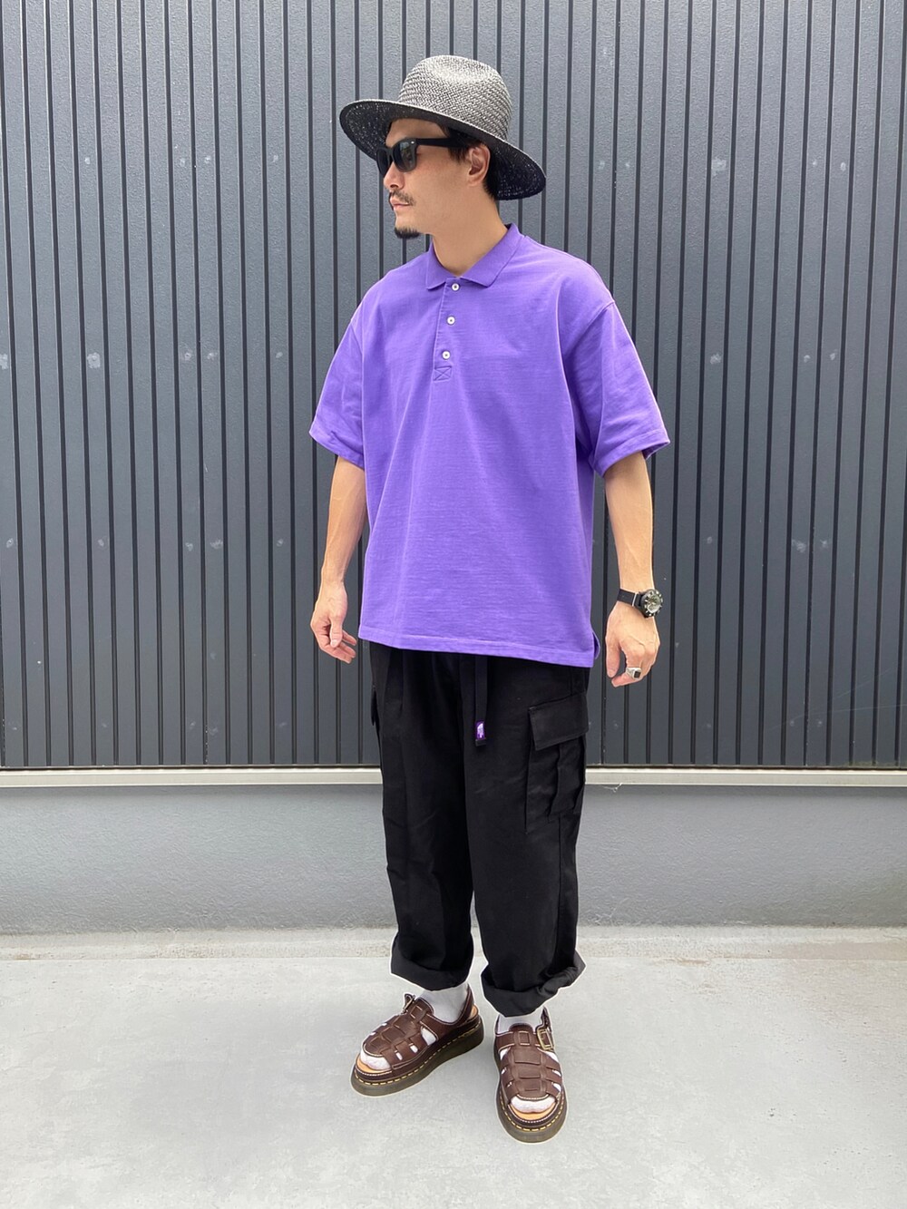 パープル系のポロシャツ、ブラック系のカーゴパンツ、ブラウン系のシューズを着用したメンズの夏コーディネートの3枚目の写真
