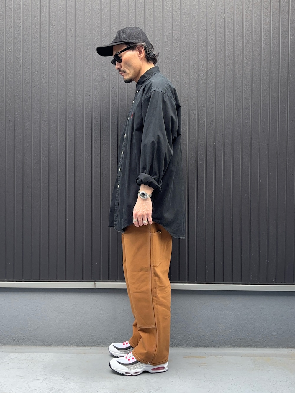 グリーン系のシャツ/ブラウス、ブラウン系のパンツ、レッド系のスニーカーを着用したメンズの春コーディネートの2枚目の写真