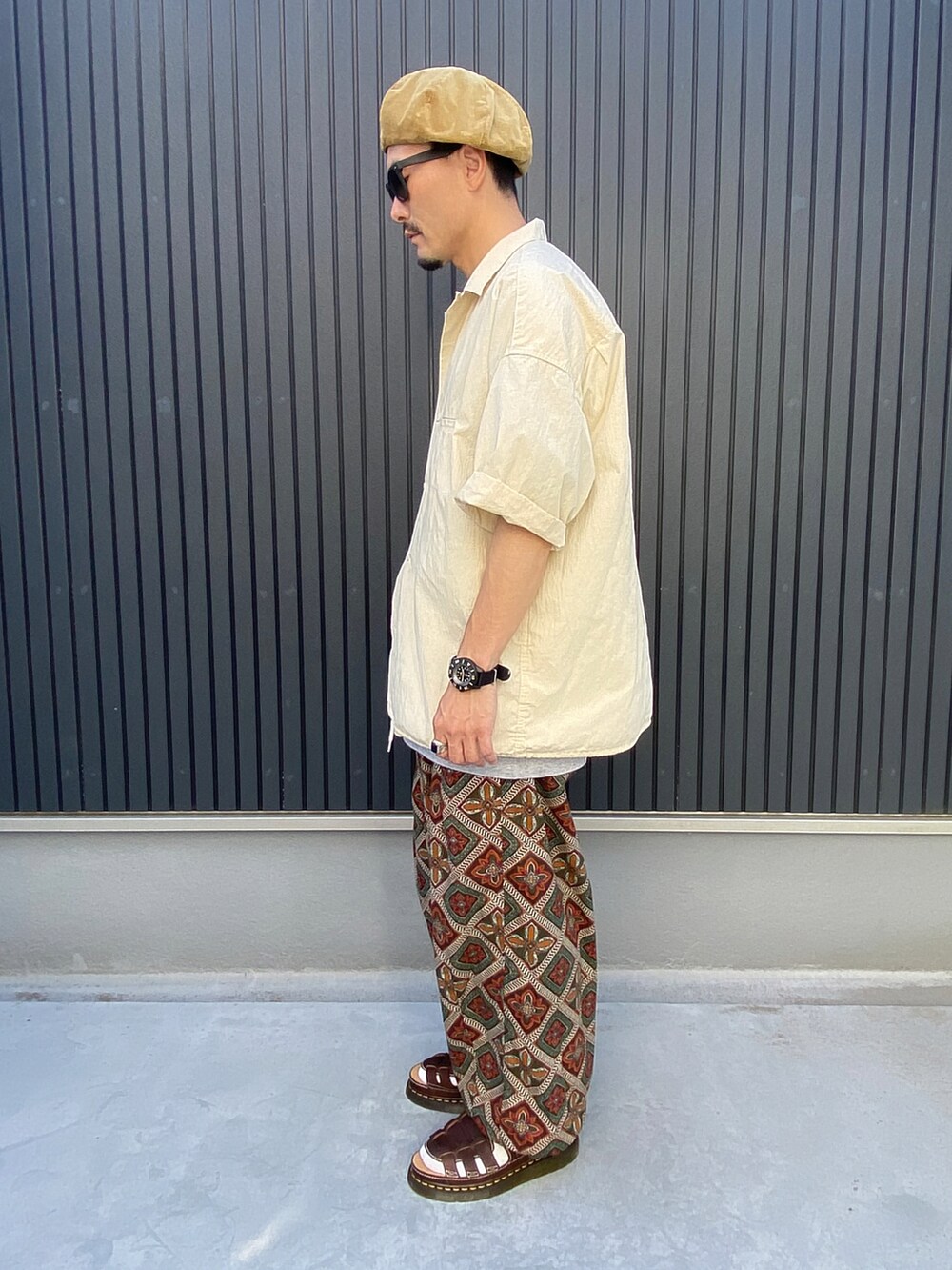 ベージュ系のトップス、グレー系のTシャツ/カットソー、ブラウン系のシューズを着用したメンズの夏コーディネートの2枚目の写真