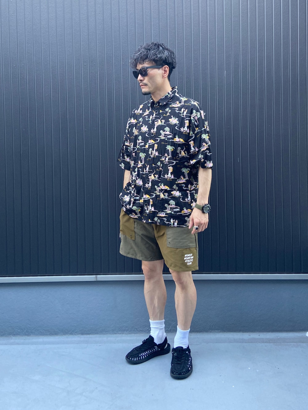 ブラック系のシャツ/ブラウス、ベージュ系のパンツ、ブラック系のサンダルを着用したメンズの夏コーディネートの3枚目の写真