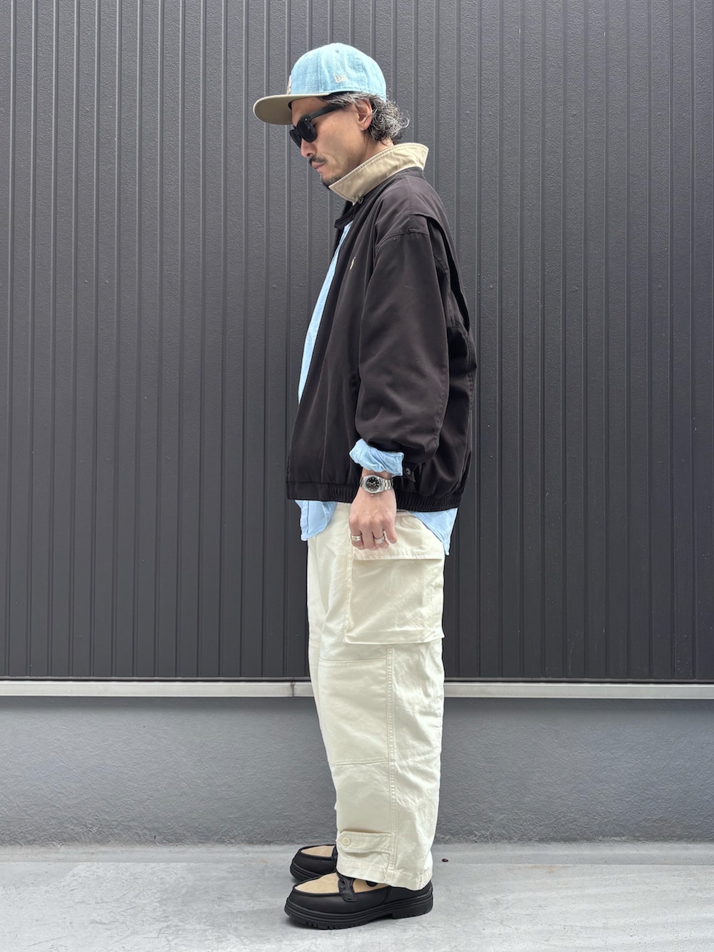 ブルー系のシャツ/ブラウス、ブラック系のジャケット/アウター、ホワイト系のカーゴパンツを着用したメンズの春コーディネートの2枚目の写真