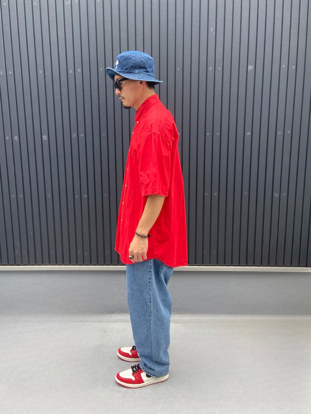 レッド系のシャツ/ブラウス、ブルー系のデニムパンツ、レッド系のスニーカーを着用したメンズの秋コーディネートの2枚目の写真