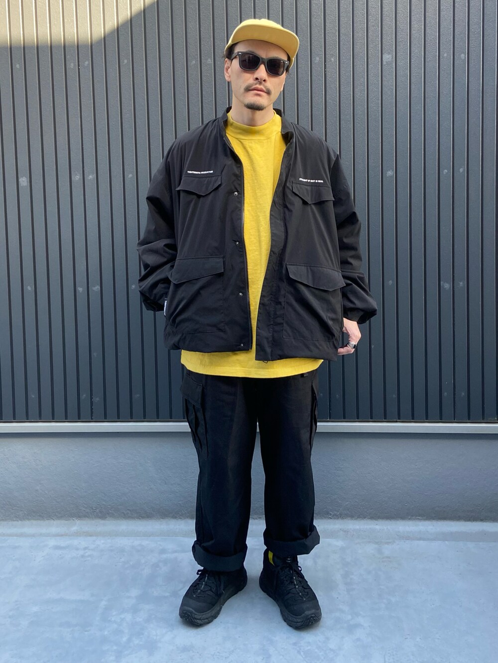 ブラック系のジャケット/アウター、イエロー系のトップス、ブラック系のカーゴパンツを着用したメンズの冬コーディネートの3枚目の写真