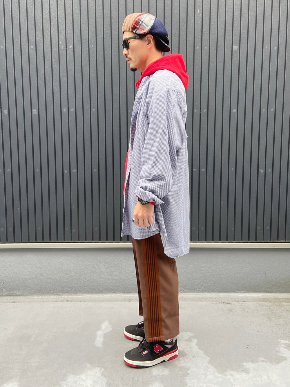 レッド系のパーカー、ブラウン系のパンツ、ブラック系のスニーカーを着用したメンズの秋コーディネートの2枚目の写真