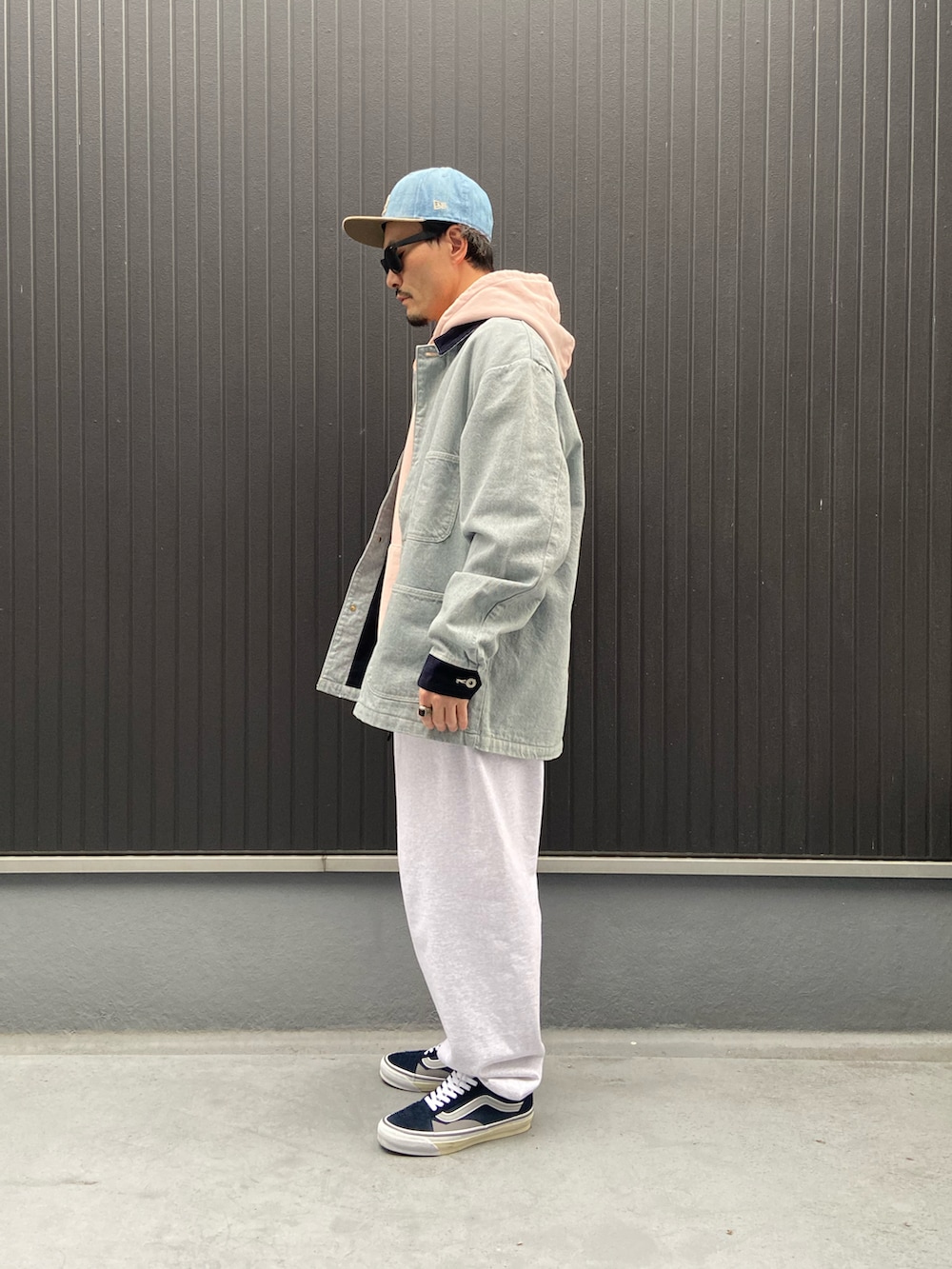 ブルー系のカバーオール、ピンク系のパーカー、グレー系のスウェットパンツを着用したメンズの冬コーディネートの2枚目の写真