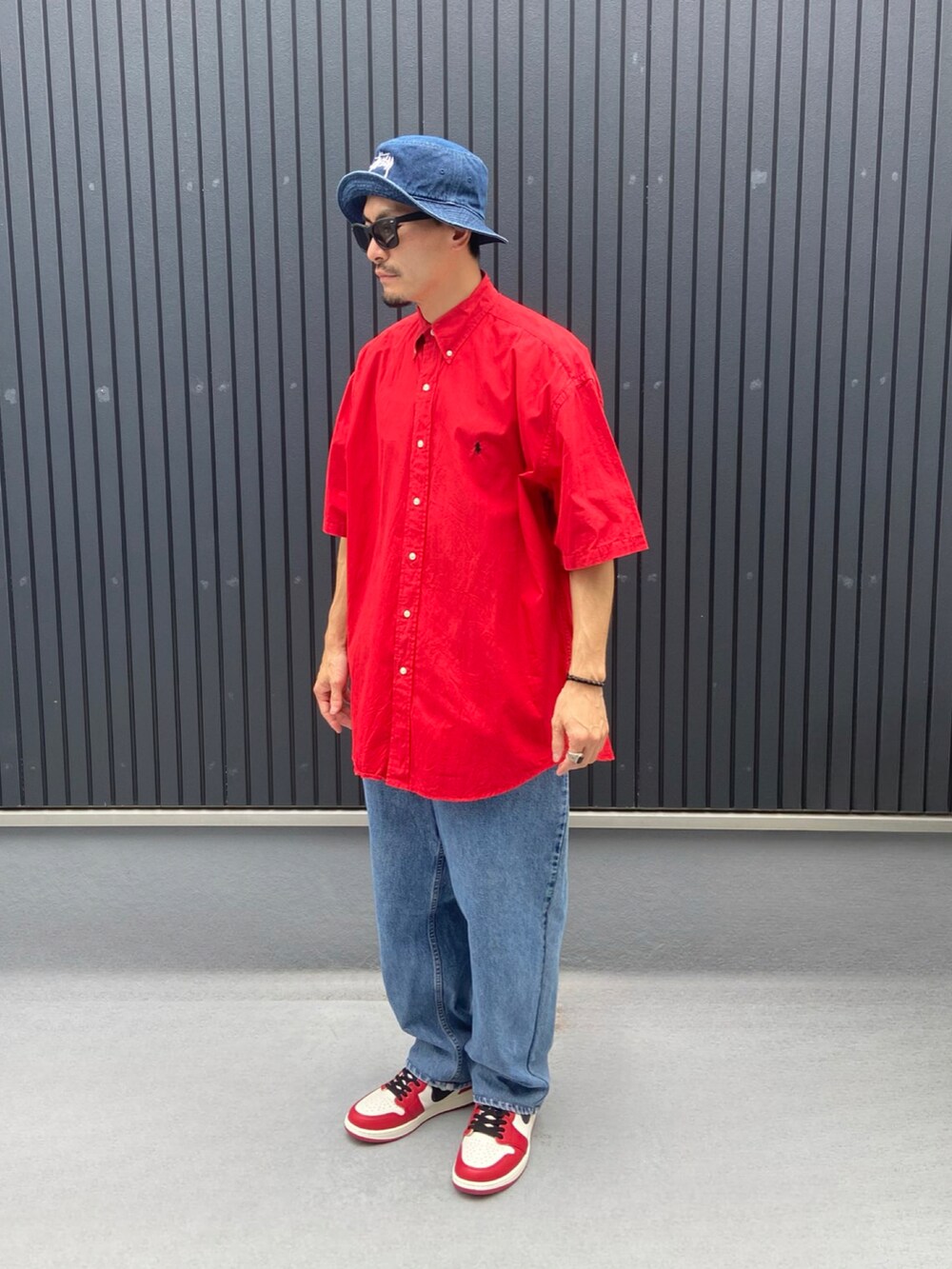 レッド系のシャツ/ブラウス、ブルー系のデニムパンツ、レッド系のスニーカーを着用したメンズの秋コーディネートの3枚目の写真