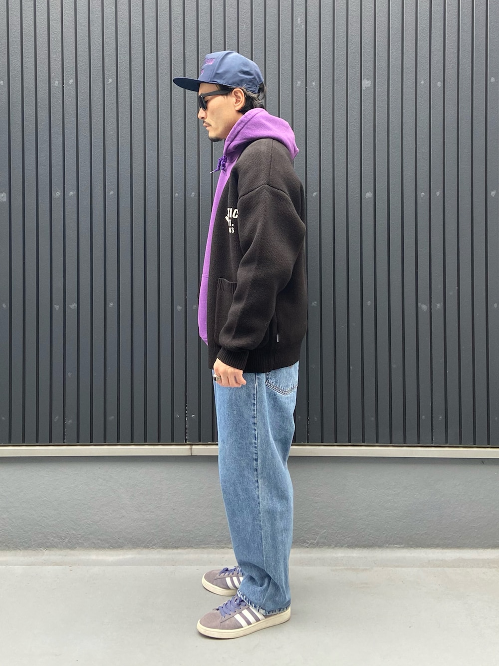 ブラック系のカーディガン/ボレロ、パープル系のパーカー、ブルー系のデニムパンツを着用したメンズの春コーディネートの2枚目の写真
