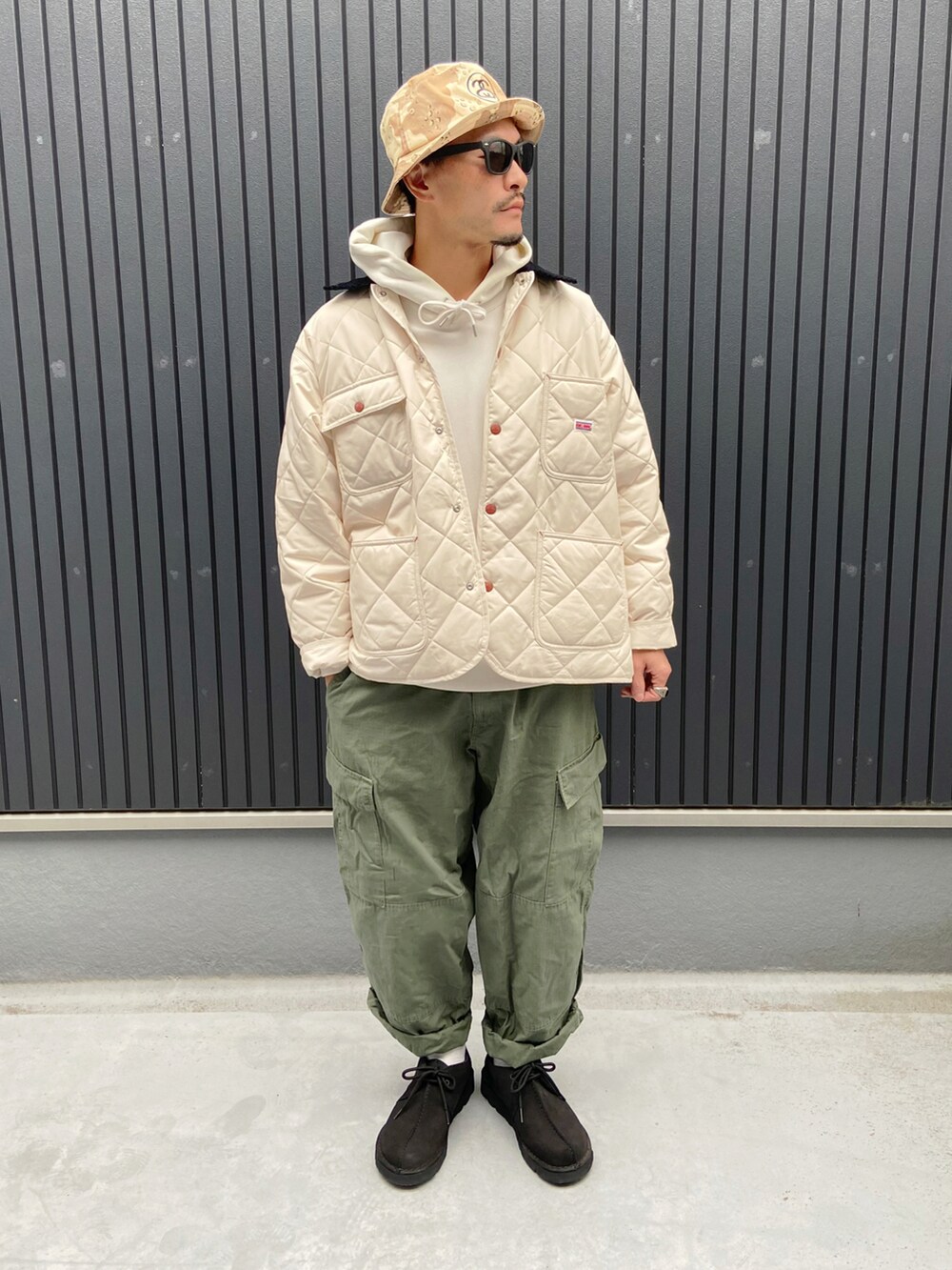 ホワイト系のカバーオール、ホワイト系のパーカー、グリーン系のパンツを着用したメンズの秋コーディネートの3枚目の写真