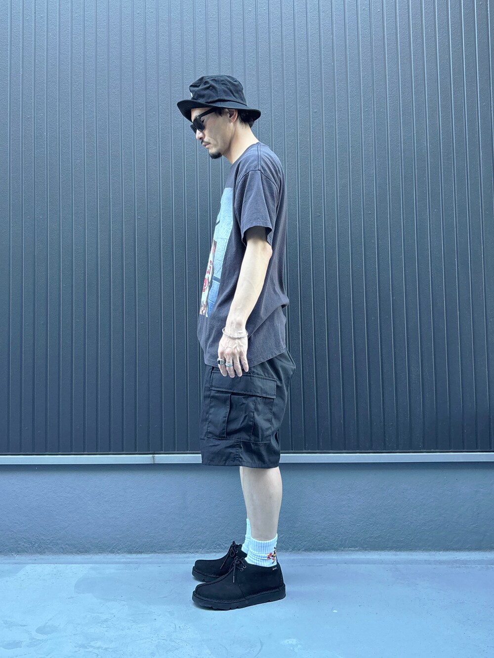 ブラック系のTシャツ/カットソー、ブルー系のモカシン/デッキシューズ、ブラック系のパンツを着用したメンズの夏コーディネートの2枚目の写真