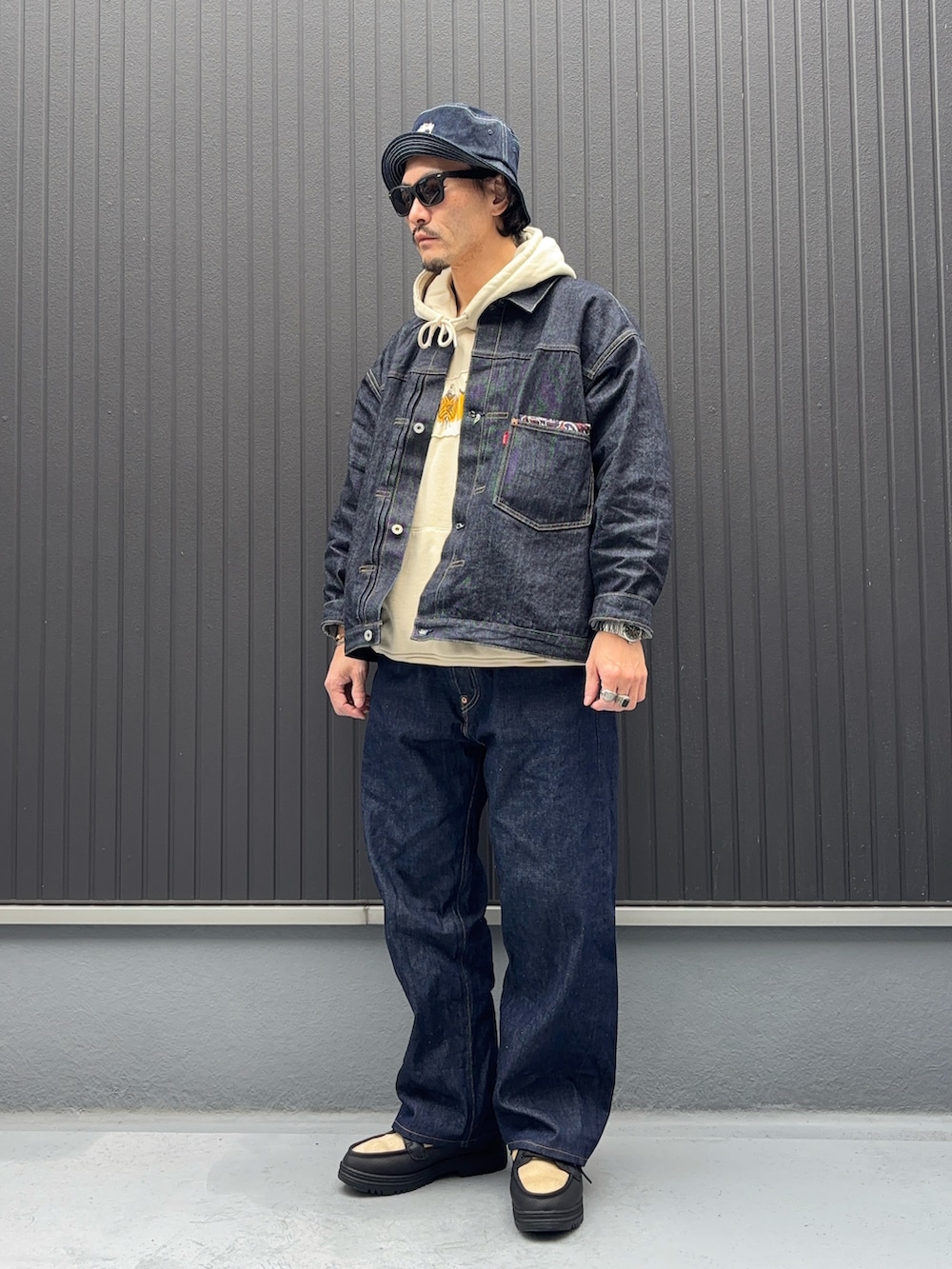 ベージュ系のパーカー、ベージュ系のパーカー、ブルー系のデニムジャケットを着用したメンズの秋コーディネートの3枚目の写真