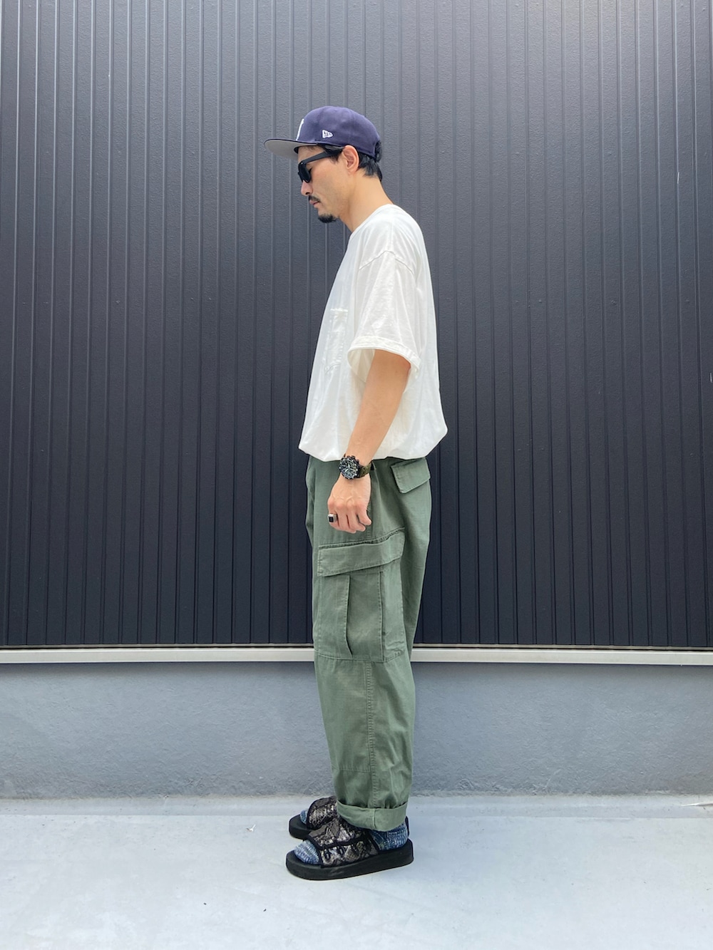 ホワイト系のTシャツ/カットソー、グリーン系のパンツ、ブラック系のシューズを着用したメンズの夏コーディネートの2枚目の写真