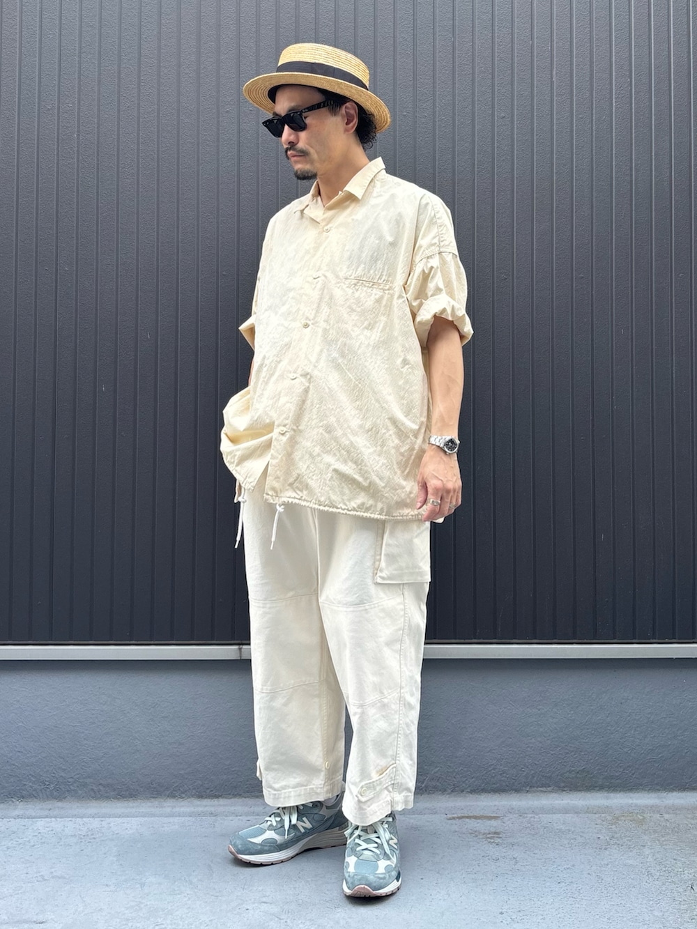 ベージュ系のトップス、ホワイト系のカーゴパンツ、グレー系のスニーカーを着用したメンズの夏コーディネートの3枚目の写真