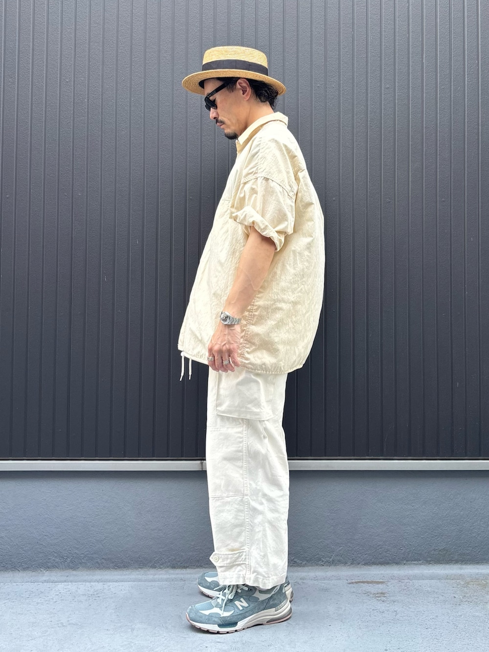 ベージュ系のトップス、ホワイト系のカーゴパンツ、グレー系のスニーカーを着用したメンズの夏コーディネートの2枚目の写真