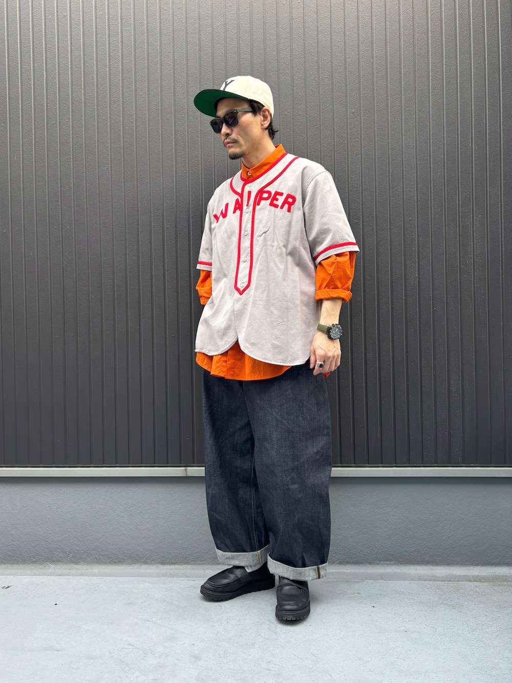 グレー系のシャツ/ブラウス、オレンジ系のトップス、ブルー系のデニムパンツを着用したメンズの春コーディネートの3枚目の写真