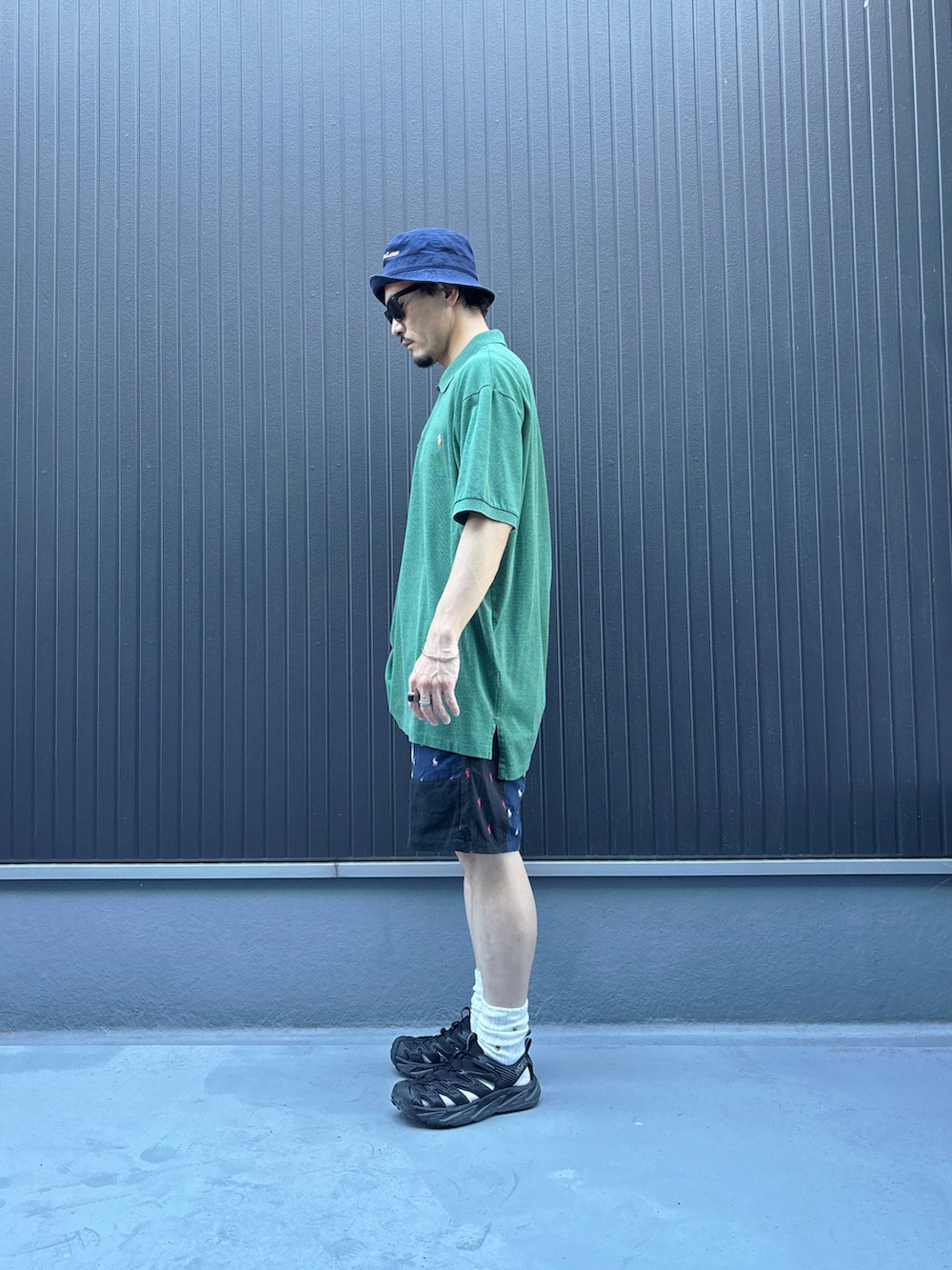 グリーン系のポロシャツ、その他のパンツ、ブラック系のサンダルを着用したメンズの夏コーディネートの2枚目の写真