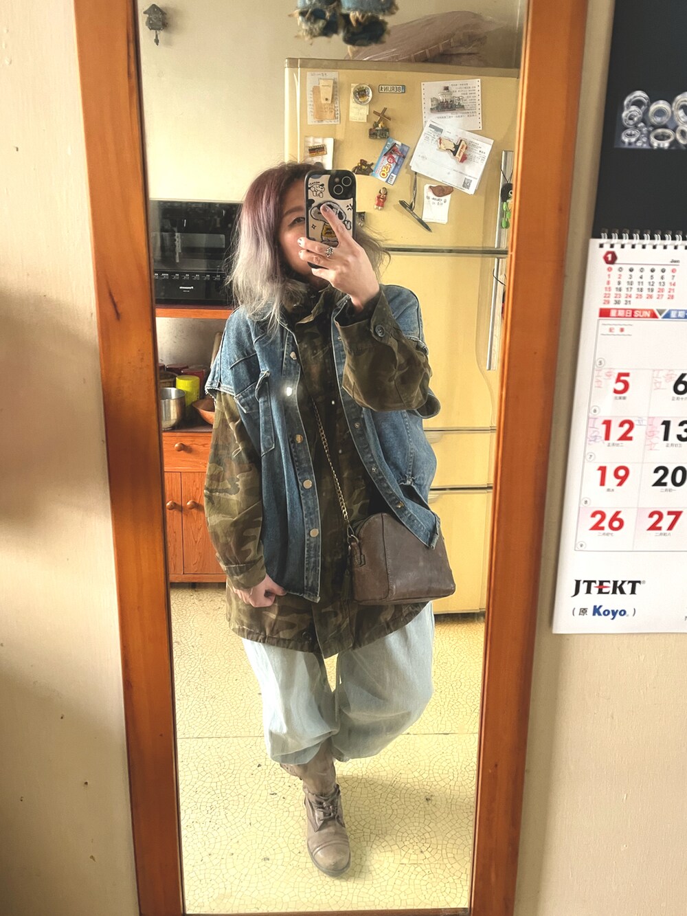 ブラウン系のショルダーバッグ、グリーン系のミリタリージャケット、ブルー系のデニムパンツを着用したレディースの冬コーディネートの2枚目の写真