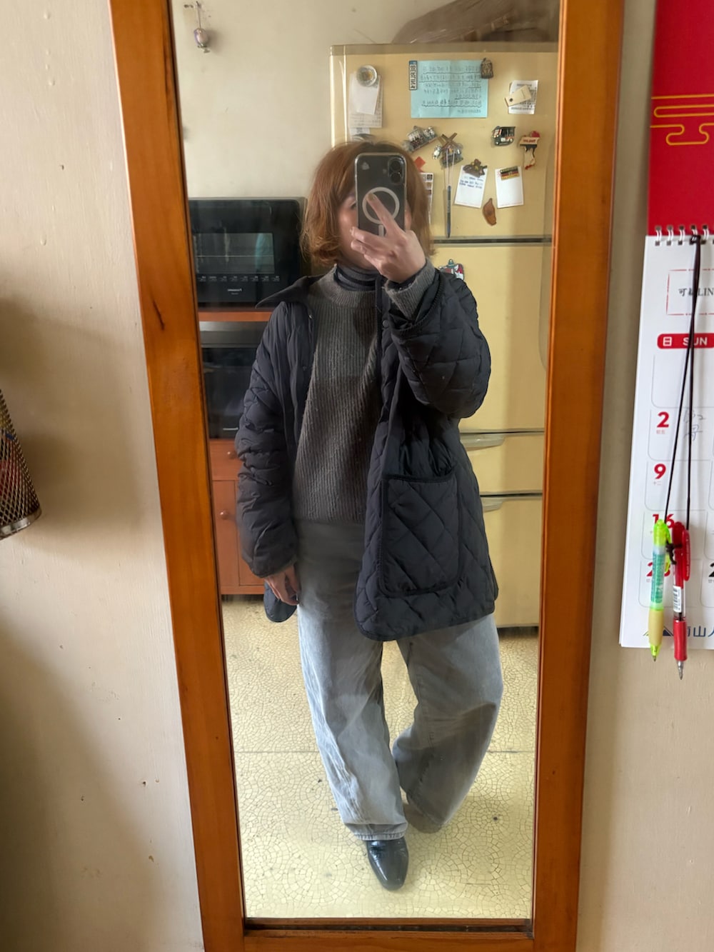 グレー系のニット/セーター、グレー系のダウンジャケット/コート、グレー系のデニムパンツを着用したレディースの冬コーディネートの2枚目の写真