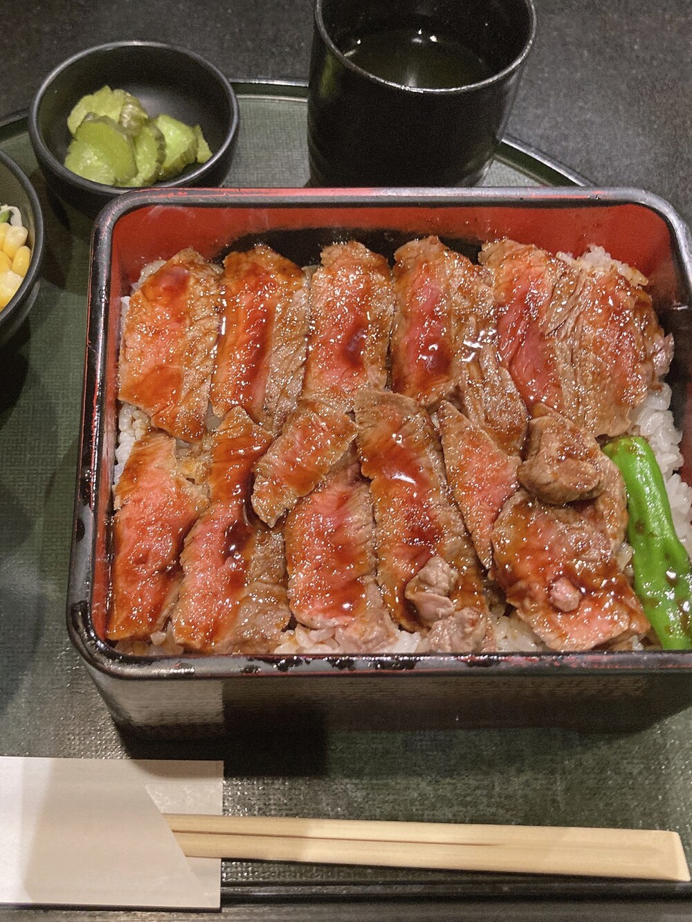 グリーン系のブルゾン、ブラック系のワンピース、ブラック系のショルダーバッグを着用したレディースの春コーディネートの3枚目の写真