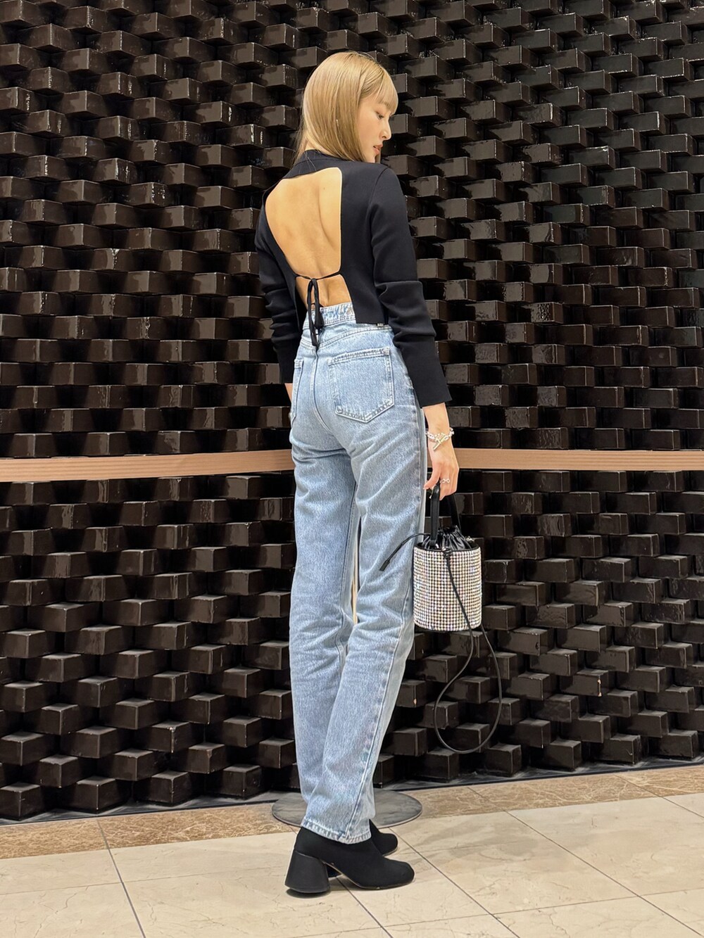 ブルー系のデニムパンツ、シルバー系のショルダーバッグ、シルバー系のブレスレットを着用したレディースの秋コーディネートの2枚目の写真