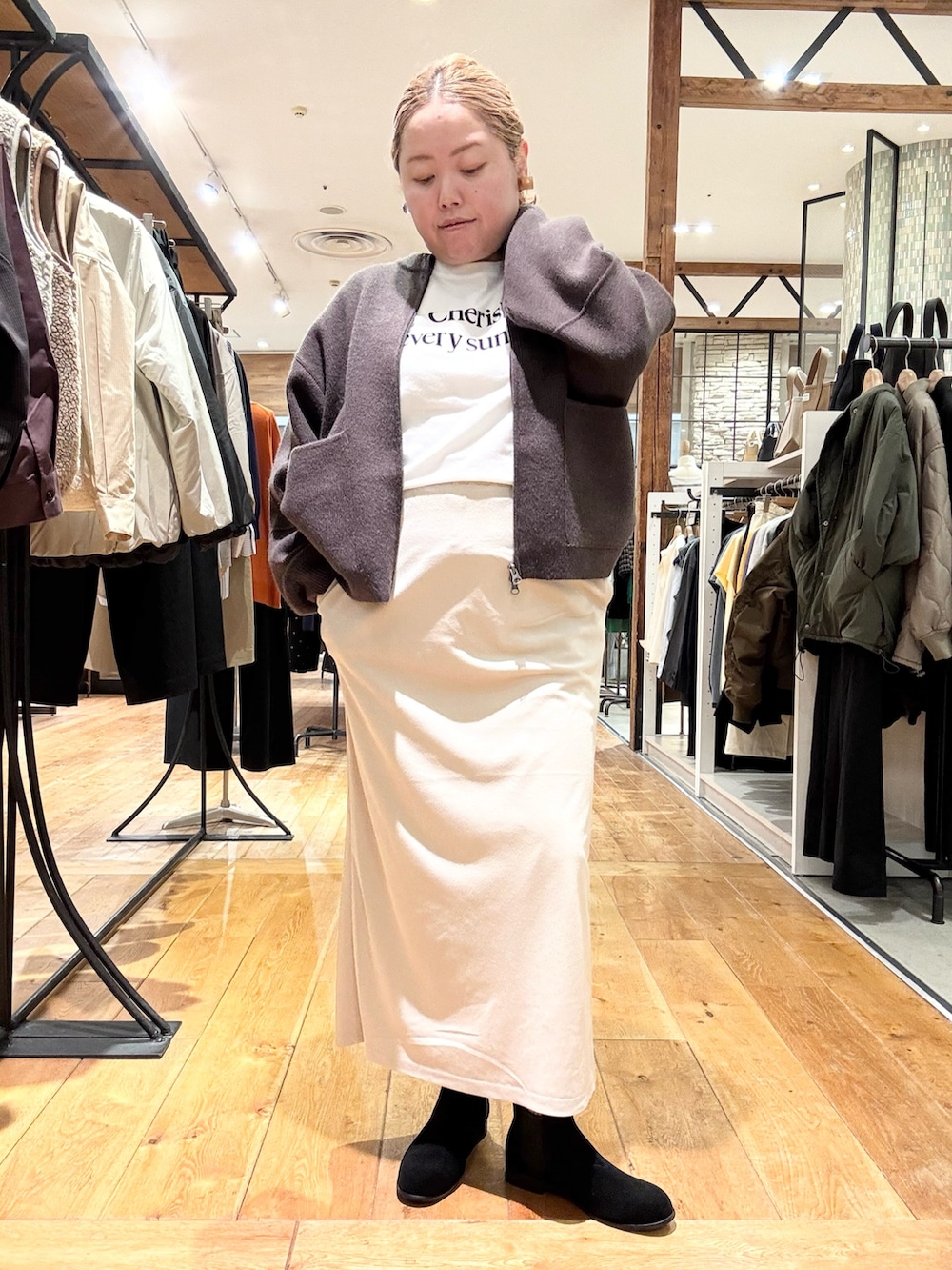 ブラウン系のブルゾン、ホワイト系のTシャツ/カットソー、ホワイト系のスカートを着用したレディースの秋コーディネートの4枚目の写真