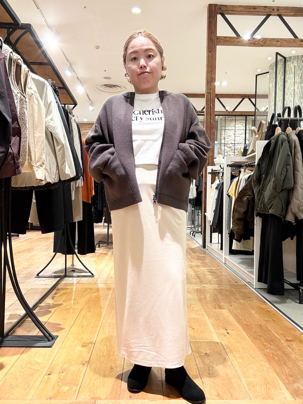ブラウン系のブルゾン、ホワイト系のTシャツ/カットソー、ホワイト系のスカートを着用したレディースの秋コーディネートの2枚目の写真