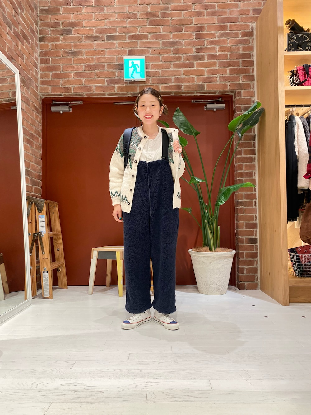 ベージュ系のニット/セーター、ブルー系のサロペット/オーバーオール、ホワイト系のスニーカーを着用したレディースの冬コーディネートの3枚目の写真