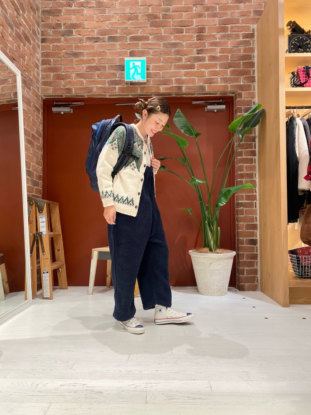 ベージュ系のニット/セーター、ブルー系のサロペット/オーバーオール、ホワイト系のスニーカーを着用したレディースの冬コーディネートの2枚目の写真