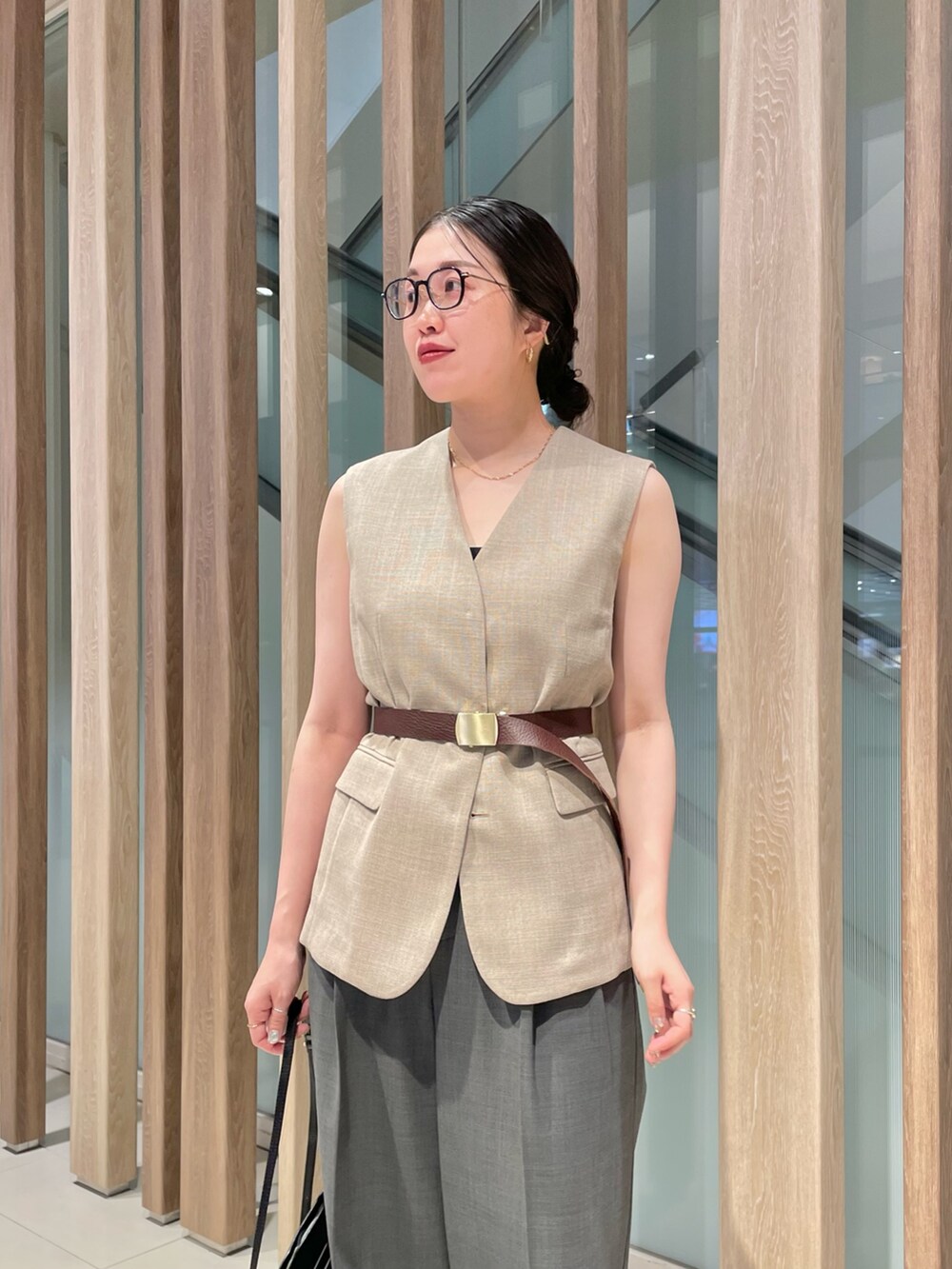 ベージュ系のベスト、ブラック系のショルダーバッグ、グレー系のスラックスを着用したレディースの春コーディネートの3枚目の写真