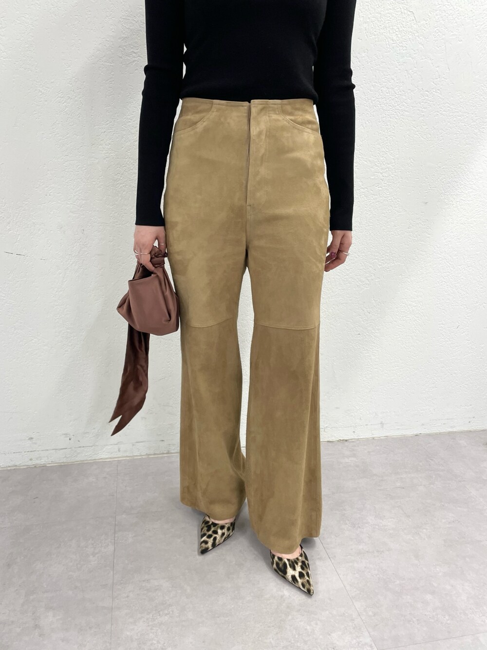 イエロー系のパンプス、イエロー系のパンツ、ブラウン系のハンドバッグを着用したレディースの冬コーディネートの4枚目の写真