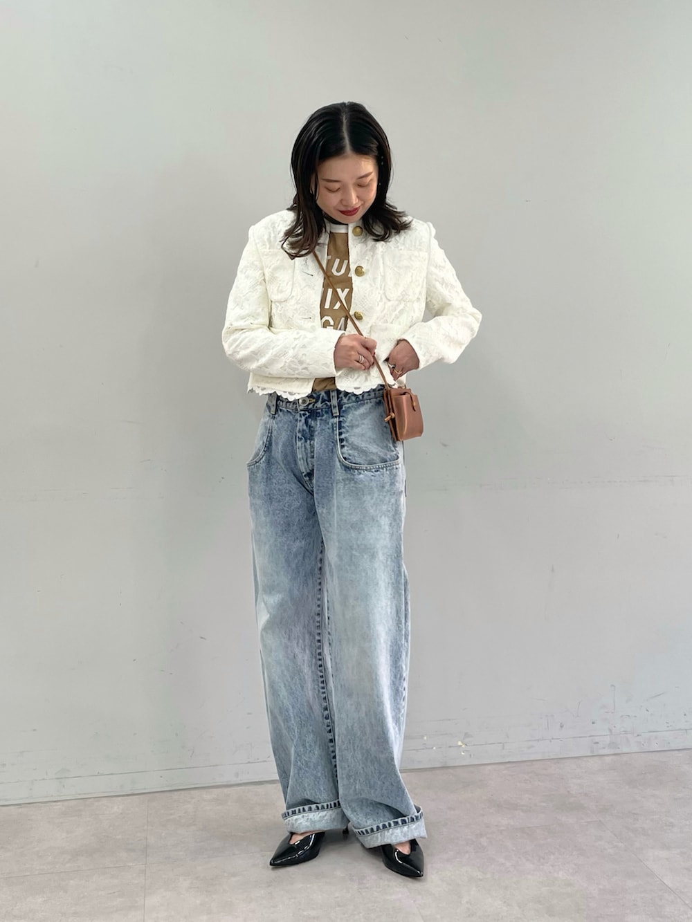 ブルー系のデニムパンツ、ブラック系のパンプス、ホワイト系のノーカラージャケットを着用したレディースの夏コーディネートの2枚目の写真