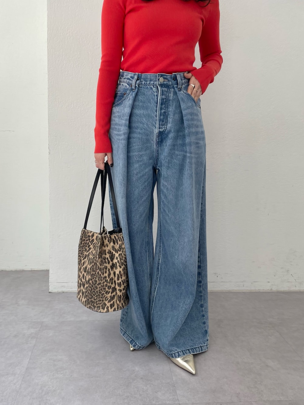 ブルー系のデニムパンツ、ゴールド系のパンプス、レッド系のニット/セーターを着用したレディースの春コーディネートの5枚目の写真