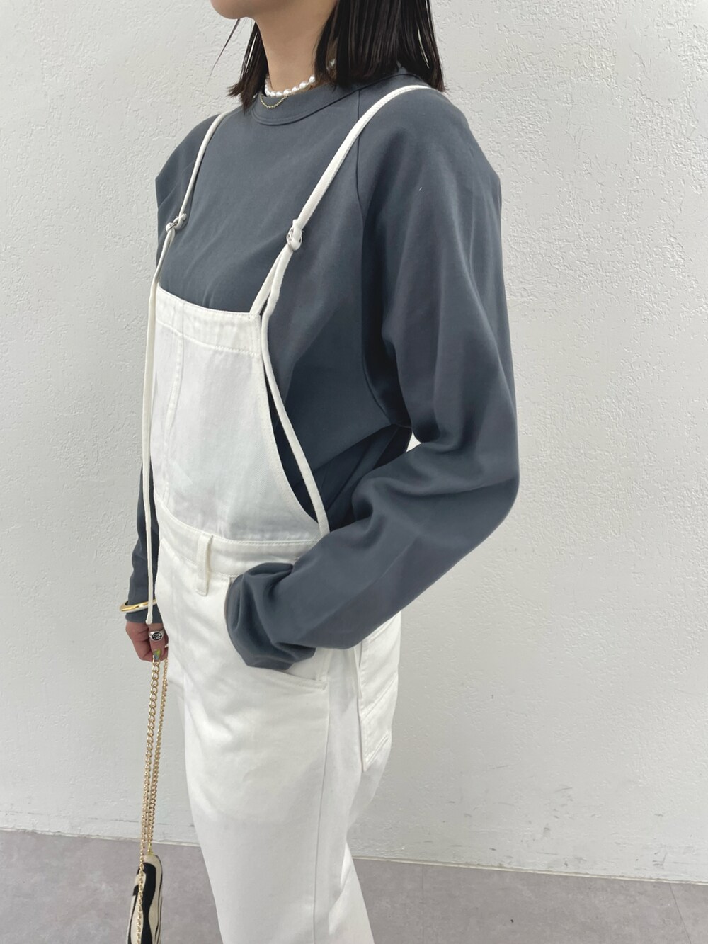 ブラック系のショルダーバッグ、ゴールド系のサンダル、ホワイト系のサロペット/オーバーオールを着用したレディースの冬コーディネートの4枚目の写真