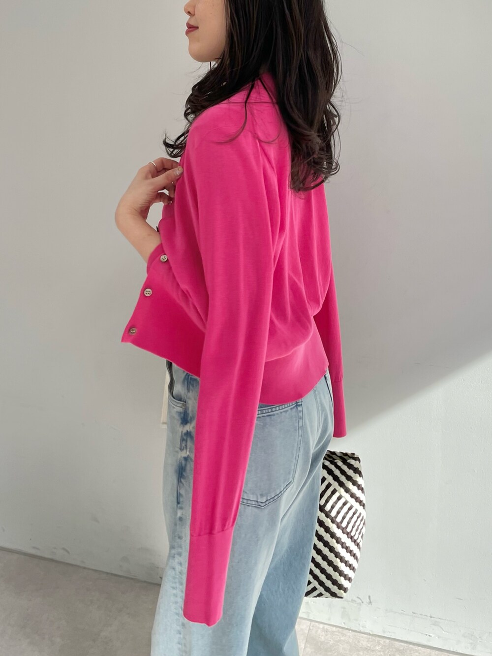 ブルー系のデニムパンツ、ブラック系のトートバッグ、ピンク系のニット/セーターを着用したレディースの春コーディネートの3枚目の写真