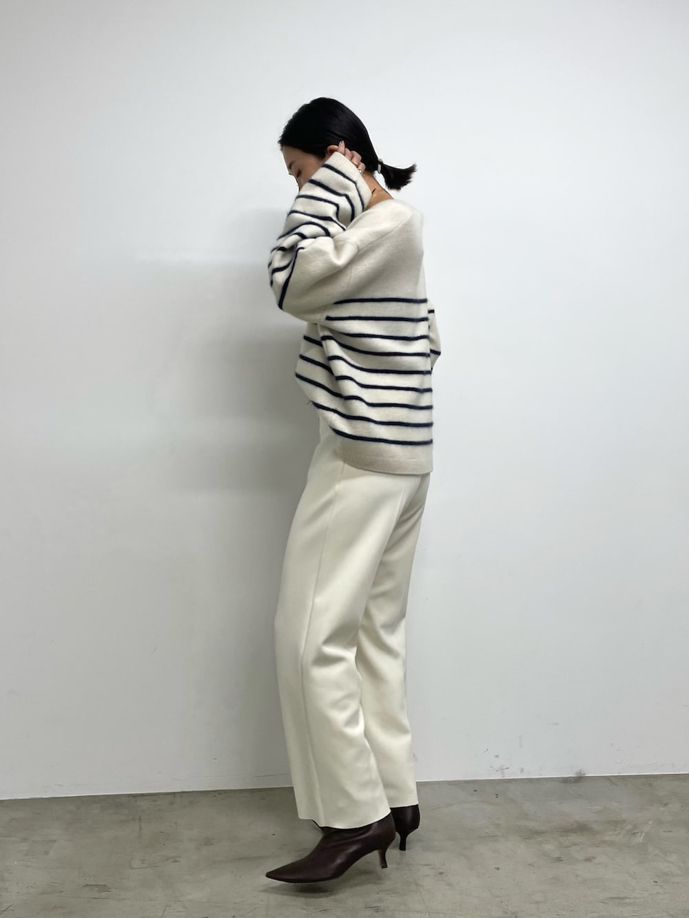 ホワイト系のスラックス、ブラウン系のブーツ、ブルー系のニット/セーターを着用したレディースの秋コーディネートの2枚目の写真