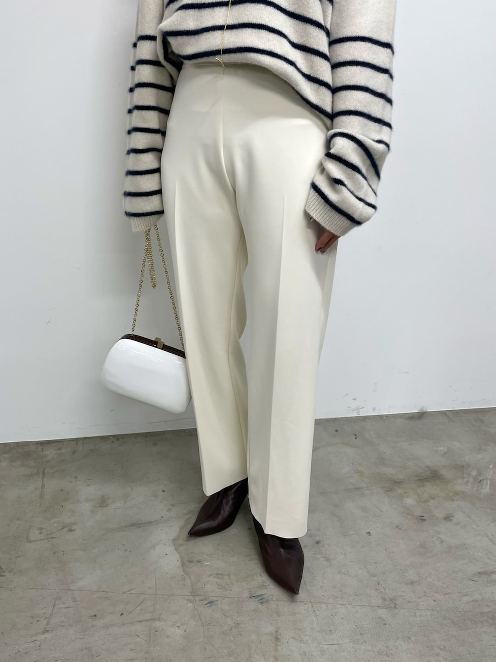 ホワイト系のスラックス、ブラウン系のブーツ、ブルー系のニット/セーターを着用したレディースの秋コーディネートの4枚目の写真