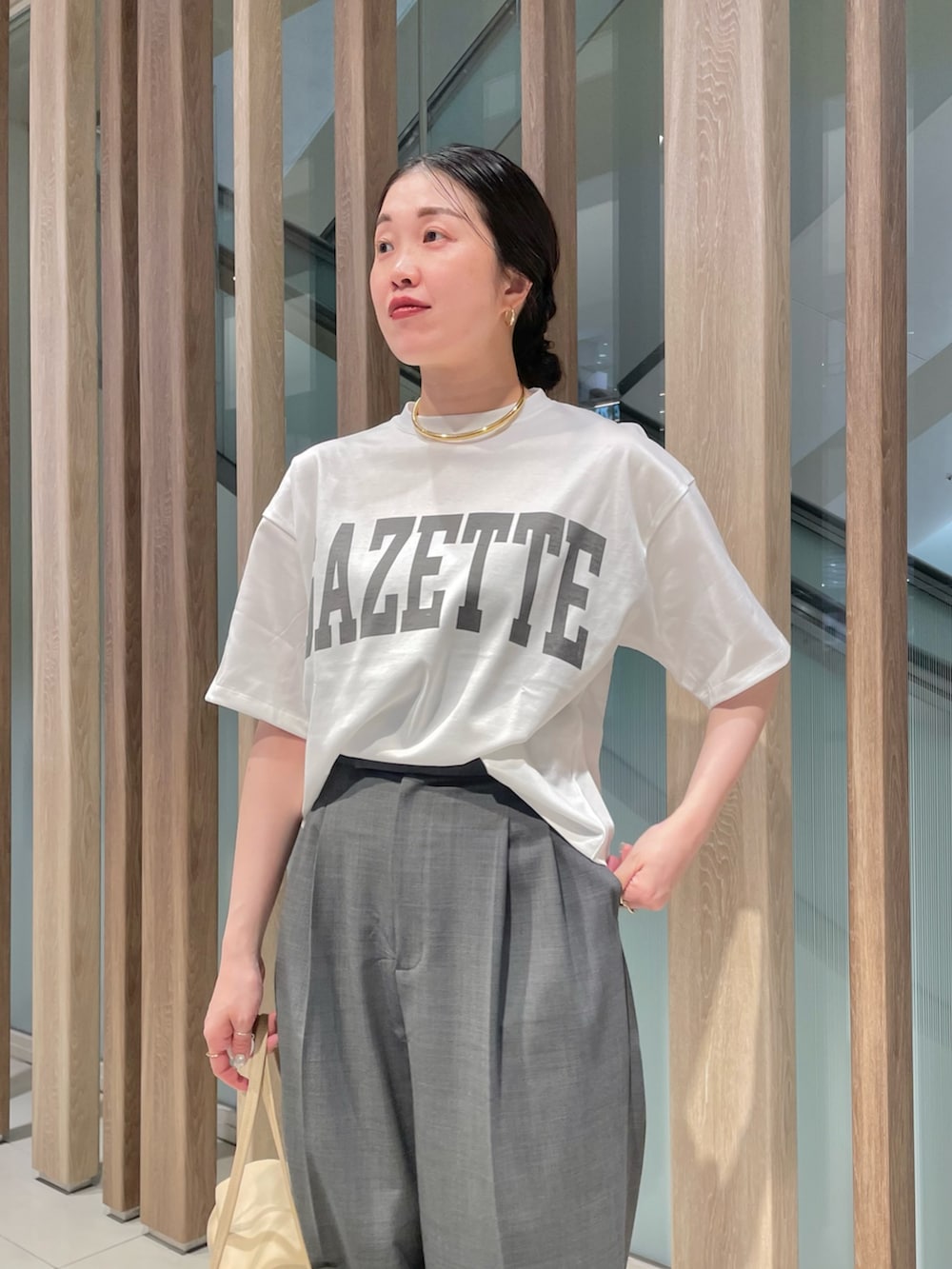 グレー系のスラックス、ベージュ系のハンドバッグ、ブラック系のサンダルを着用したレディースの春コーディネートの3枚目の写真