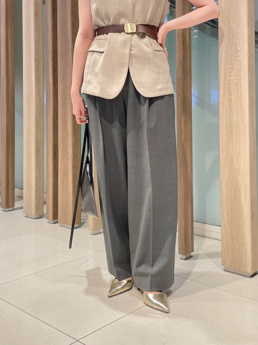 ベージュ系のベスト、ブラック系のショルダーバッグ、グレー系のスラックスを着用したレディースの春コーディネートの5枚目の写真