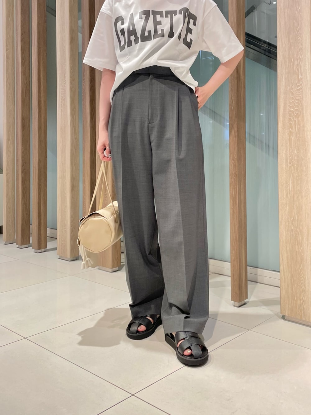 グレー系のスラックス、ベージュ系のハンドバッグ、ブラック系のサンダルを着用したレディースの春コーディネートの5枚目の写真