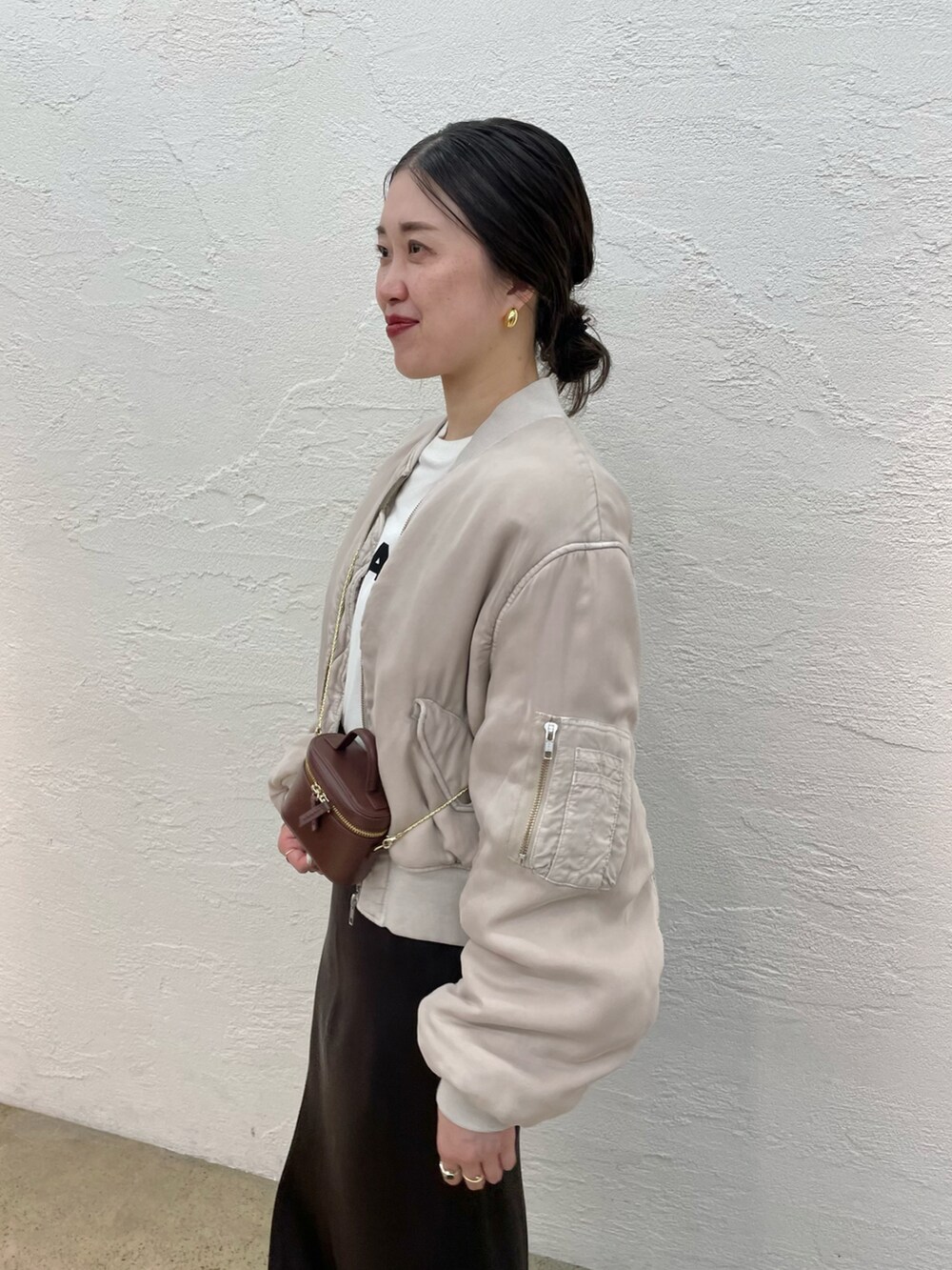 ブラック系のローファー、ブラウン系のスカート、ブラウン系のショルダーバッグを着用したレディースの夏コーディネートの3枚目の写真