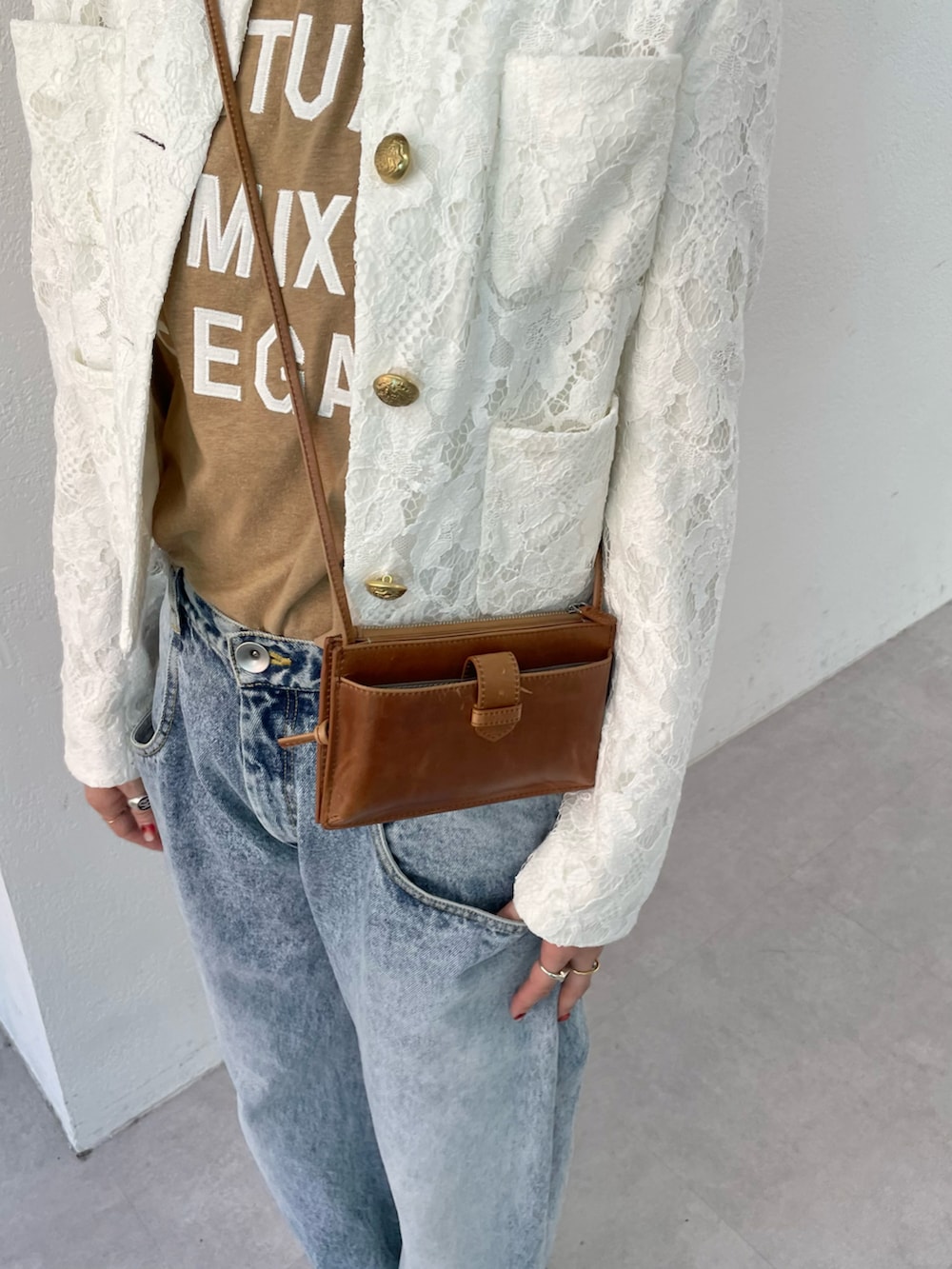 ブルー系のデニムパンツ、ブラック系のパンプス、ホワイト系のノーカラージャケットを着用したレディースの夏コーディネートの4枚目の写真