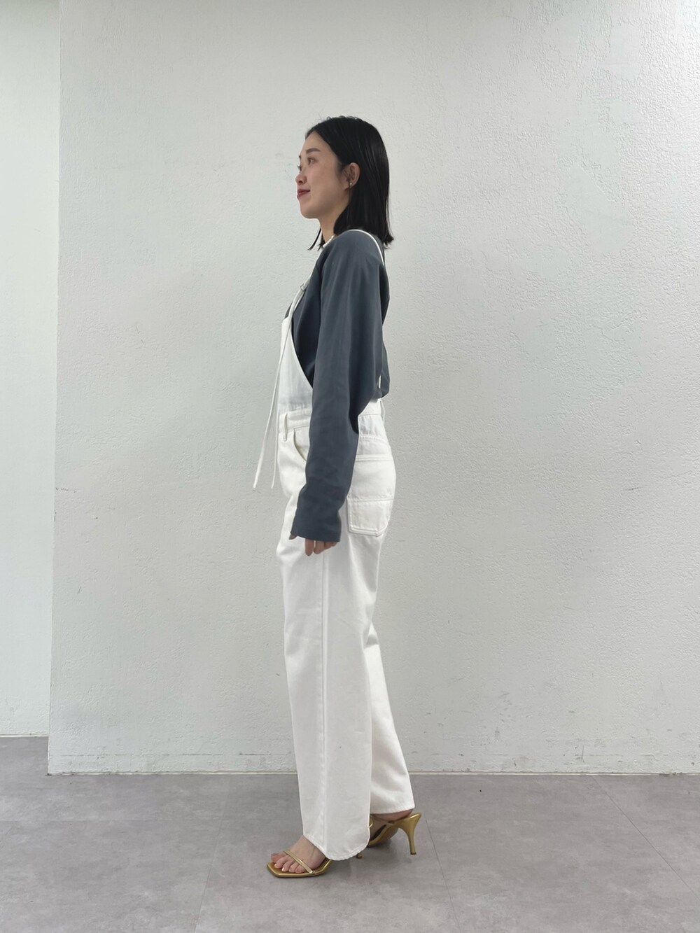 ブラック系のショルダーバッグ、ゴールド系のサンダル、ホワイト系のサロペット/オーバーオールを着用したレディースの冬コーディネートの3枚目の写真