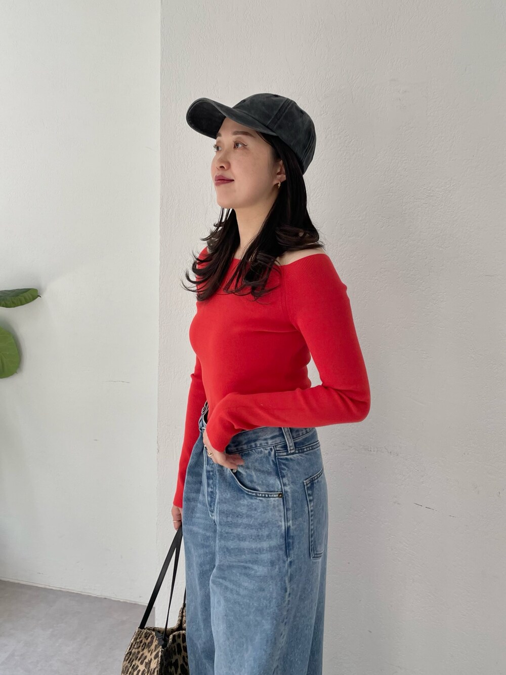 ブルー系のデニムパンツ、ゴールド系のパンプス、レッド系のニット/セーターを着用したレディースの春コーディネートの3枚目の写真