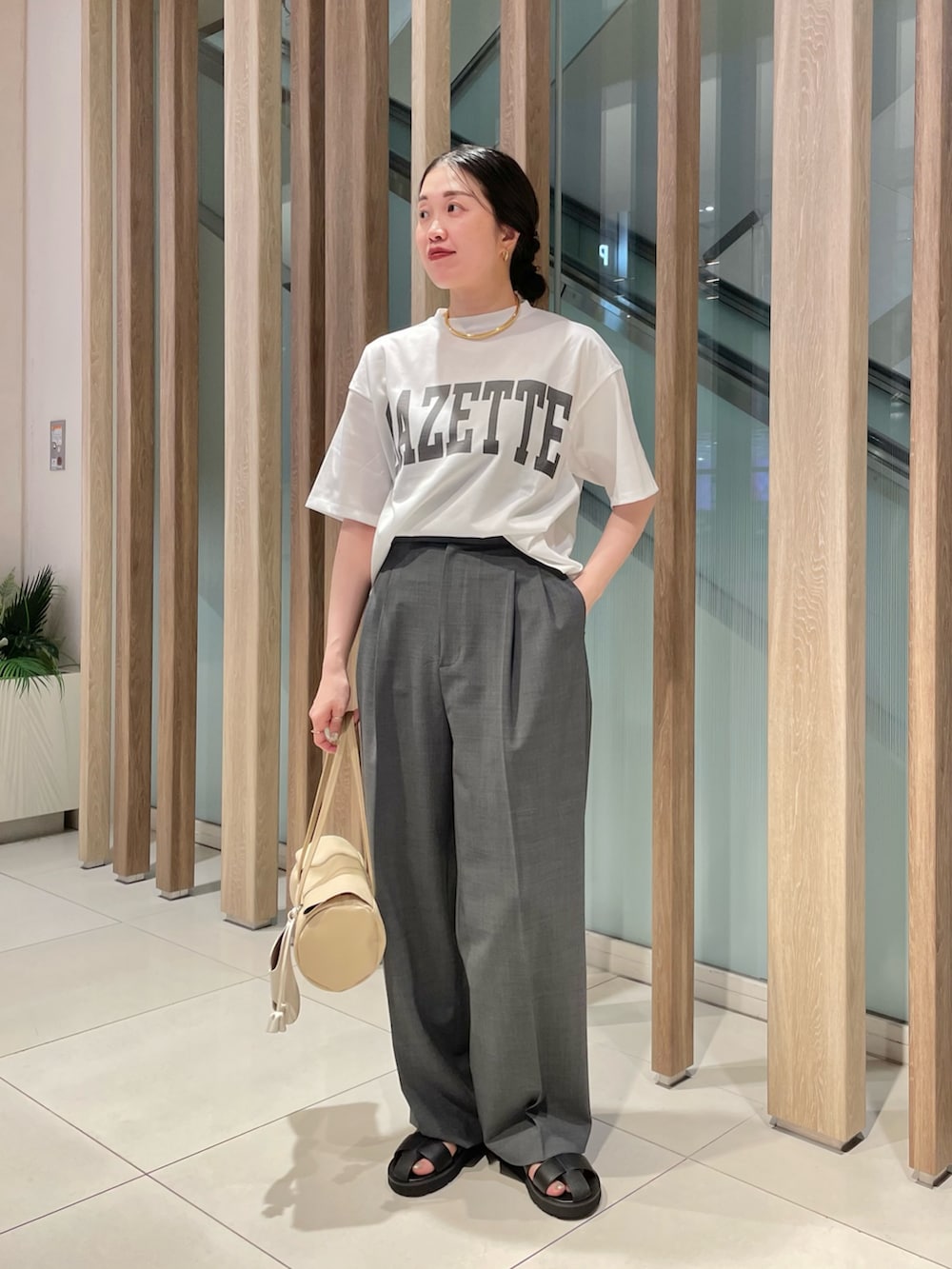 グレー系のスラックス、ベージュ系のハンドバッグ、ブラック系のサンダルを着用したレディースの春コーディネートの9枚目の写真