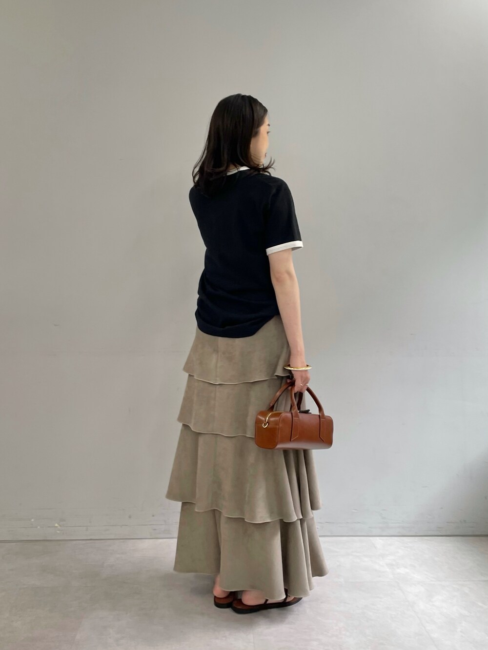 ブラック系のTシャツ/カットソー、ベージュ系のスカート、ゴールド系のブレスレットを着用したレディースの夏コーディネートの2枚目の写真