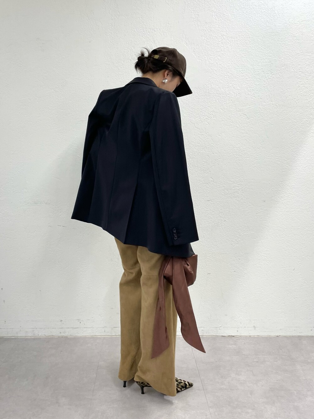 イエロー系のパンプス、イエロー系のパンツ、ブラウン系のハンドバッグを着用したレディースの冬コーディネートの2枚目の写真